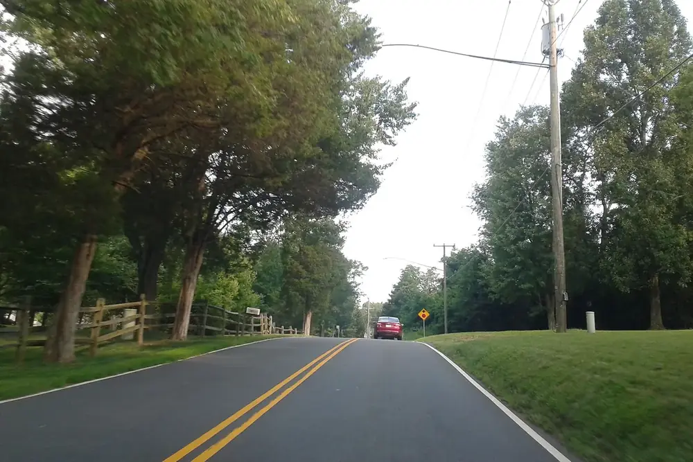 Tree-lined two-lane road with a split-rail fence in Wolf Trap, Virginia